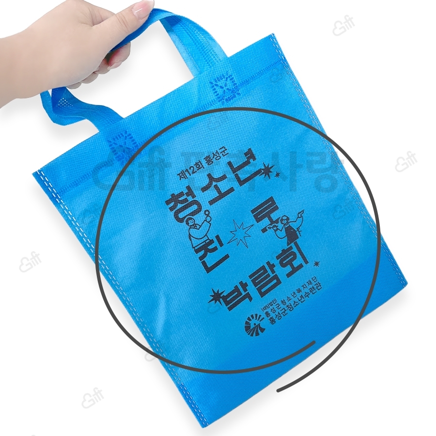 파란색 손잡이 부직포 가방 앞면에 행사용 글자가 인쇄된 공식 납품사례 사진